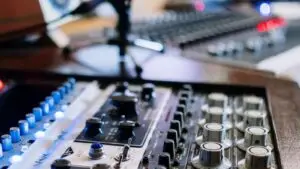 Radio studio mixing console and microphone - Marketing Agency in Branson MO | Smart & Simple Communications - Marketing Agency in Branson MO | Smart & Simple Communications Close up of a radio studio mixing console with illuminated controls and a microphone stand, where radio advertising spots are produced