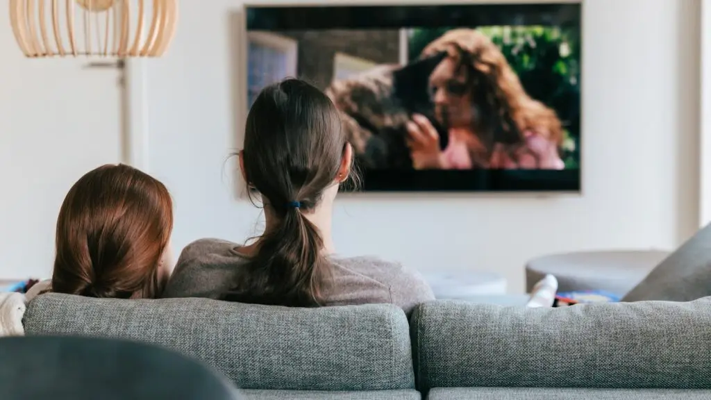 Two people watching streaming television on a wall mounted screen in a living room, the audience a Branson business can reach with CTV advertising