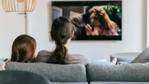 Two people watching streaming television on a wall mounted screen in a living room, the audience a Branson business can reach with CTV advertising