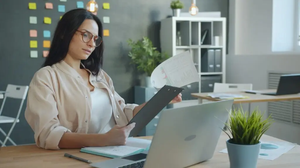 Ozarks small business owner reviewing her plain English monthly SEO report, with charts, a notebook, and a laptop on her desk