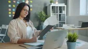 what-does-an-seo-company-do-each-month - Smart & Simple Communications - Smart & Simple Communications Ozarks small business owner reviewing her plain English monthly SEO report, with charts, a notebook, and a laptop on her desk