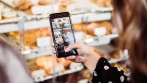 what-to-post-on-social-media-small-business - Marketing Agency in Branson MO | Smart & Simple Communications - Marketing Agency in Branson MO | Smart & Simple Communications Ozarks bakery owner photographing her pastry case on her phone to create a social media post