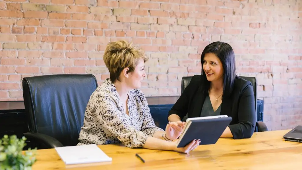 Small business owner meeting with a marketing agency partner to review a growth plan on a tablet at a wood table