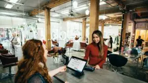 How to get more Google reviews - Smart & Simple Communications - Smart & Simple Communications Shop owner smiling with a customer at the checkout counter of a local business, the moment when asking for a Google review works best