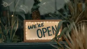 Local SEO checklist for Ozarks businesses - Smart & Simple Communications - Smart & Simple Communications A lit we are open sign glowing in the window of a small independent shop behind trailing plants, the kind of local Ozarks business a local SEO checklist helps nearby customers find